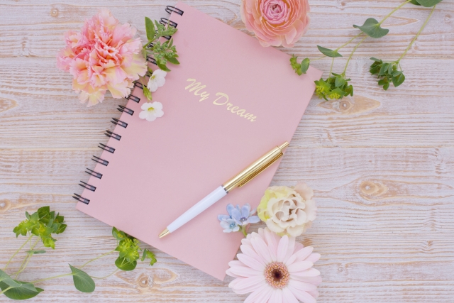 花に囲まれたノートとペン
